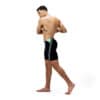 גבר לובש בגדי ים של Speedo, עומד על רגל אחת, מוכן לשחייה.
