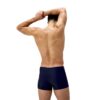 גבר בוחן בגד ים קצר של Speedo, מראה את עיצובו והחומר.