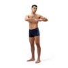 גבר לובש בגד ים שחייה של Speedo, עומד עם ידיים פרוסות.