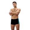 גבר לובש בגד ים שחור עם דוגמה כחולה של Speedo, מוכן לשחייה.
