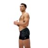 גבר לובש בגד ים שחור של Speedo, מוכן לשחייה או ספורט מים.