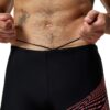גבר במדים של Speedo, בגד ים שחור עם עיצוב אדום, מוכן לשחייה.