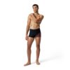 גבר לובש בגד ים קצר שחור ואדום של Speedo, עומד מול רקע לבן.