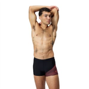 גבר לובש בגד ים ספורטיבי של Speedo, עומד עם ידיים מאחורי הר.