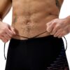 גבר מחזיק במותניו בגדי ים של Speedo, ספורטיבי ומודרני.